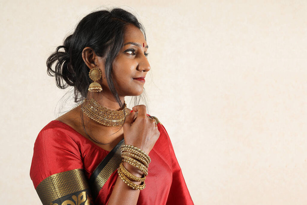 Kırmızı turuncu sari takısı takan Hintli bir kadın. Kolye, jhumka küpe, maang tikka bel zinciri poz. Eski kırsal oda arka planında gülücük ruh haline bakın. - Fotoğraf, Görsel