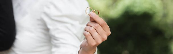 cropped view of bride holding wedding golden rings in hand, banner - Photo, image