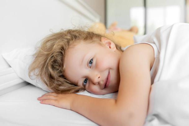 The child lies quietly in bed and smiles. - Foto, Bild