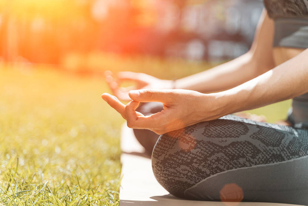 Nainen meditoi lootusasennossa ja rentouttaa luonnossa puistossa kesällä aurinkoisella säällä. Jooga, mielenterveys, rentoutuminen, terveyskäsite. Laadukas kuva - Valokuva, kuva