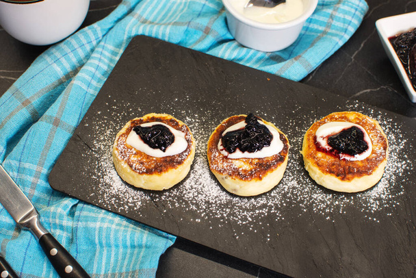 Zoete kaas pannenkoeken op bord geserveerd aardbeien. Syrniki, ricotta-beignets, wrongelbeignets. - Foto, afbeelding