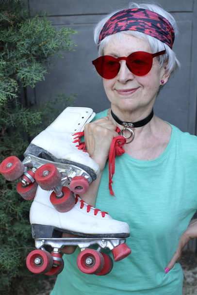 close-up portrait of mature woman with sunglasses and vintage roller skates - Photo, Image