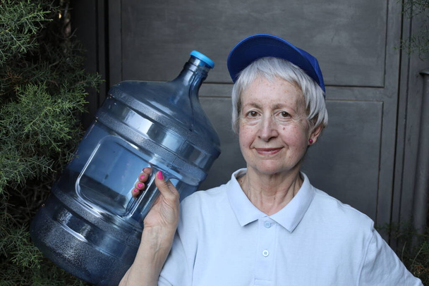 close-up portret van volwassen vrouw uit water levering dienst met grote water fles - Foto, afbeelding