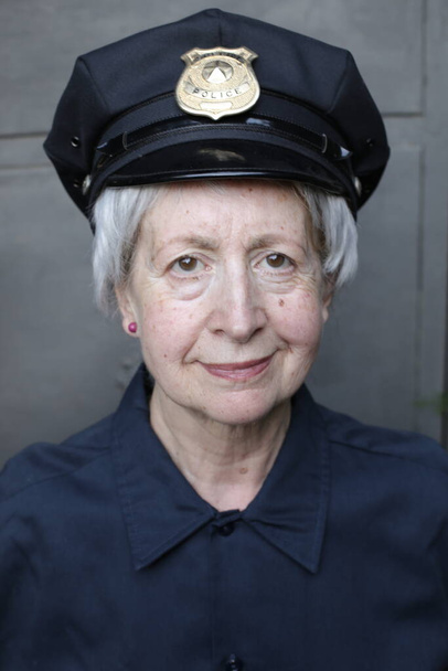 close-up portrait of mature woman in police uniform on grey wall background - Photo, Image