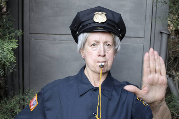 close-up portrait of mature woman in police uniform on grey wall background - Photo, Image