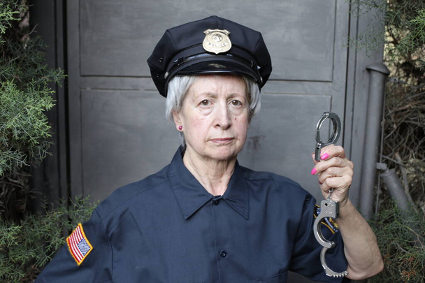 Nahaufnahme Porträt einer reifen Frau in Polizeiuniform auf grauem Wandhintergrund - Foto, Bild