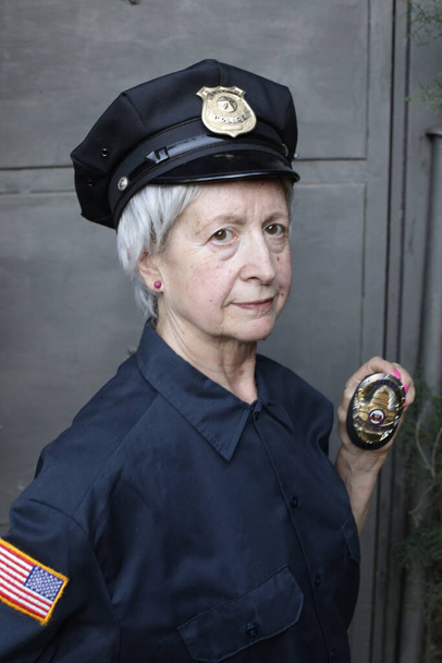 portrait en gros plan de femme mature en uniforme de police sur fond de mur gris - Photo, image