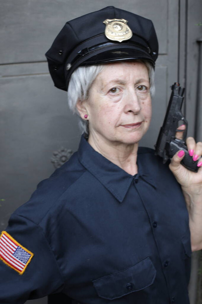 retrato de cerca de mujer madura en uniforme de policía sobre fondo gris de la pared - Foto, imagen