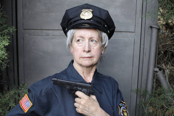 Nahaufnahme Porträt einer reifen Frau in Polizeiuniform auf grauem Wandhintergrund - Foto, Bild