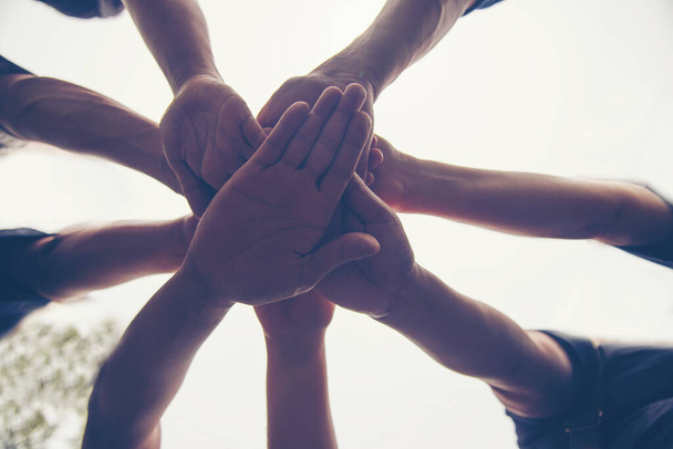 Mladí lidé dávají své ruce dohromady na vrch druhých.Solidarita spojuje lidi ruku v ruce s týmovou prací komunity.  - Fotografie, Obrázek