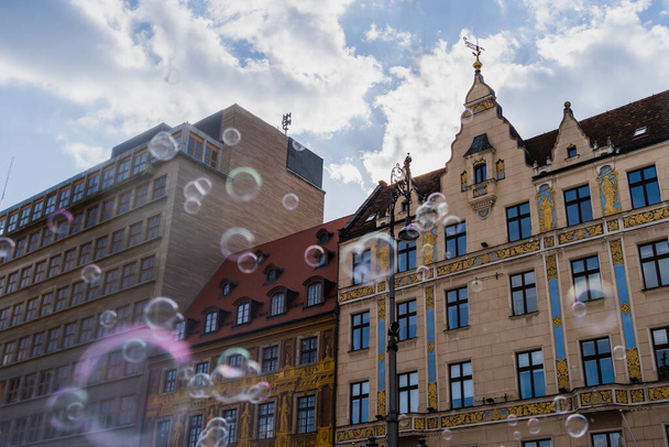Vista de baixo ângulo de bolhas de sabão borradas e edifícios na rua em Wroclaw - Foto, Imagem