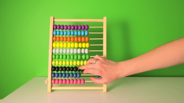 Female hand slowly counts on a childrens wooden abacus. Close-up of flipping wooden circles. Counting on a childrens account - Footage, Video