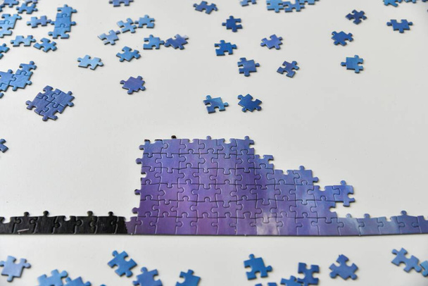 Verspreide puzzels liggen op tafel en een deel van de geassembleerde foto. - Foto, afbeelding