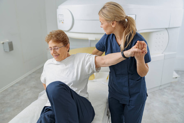 Ακτινολόγος βοηθήσει να καθίσει ο ασθενής μετά από τη διαδικασία της μαγνητικής τομογραφίας ή αξονικής τομογραφίας. Ιατρικός εξοπλισμός υψηλής τεχνολογίας - Φωτογραφία, εικόνα