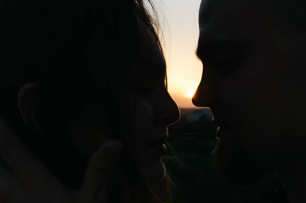 Sziluett egy férfiról és egy nőről, akik megérintik egymás homlokát naplementekor. - Fotó, kép