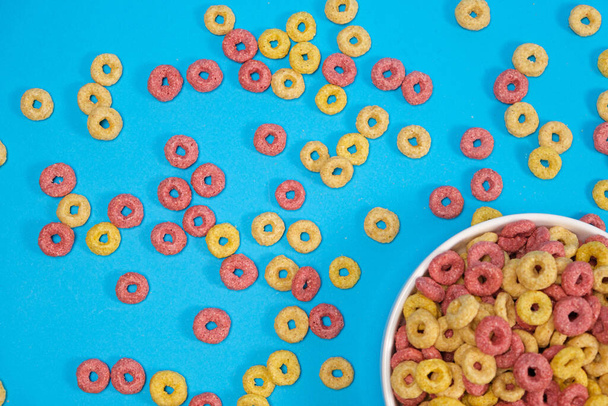 Corn rings of quick breakfast powder on a plate on a blue background, top view. - Photo, image