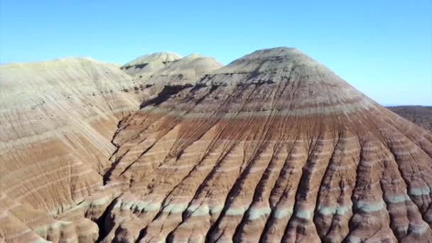 Gekleurde bergen van Aktau in de steppe. Kalkstenen bergen in het midden van de woestijn. Gekleurde heuvels van wit tot rood. Het aardegesteente wordt gescheiden door lagen. Een enorme kloof. Altyn Emel. - Video