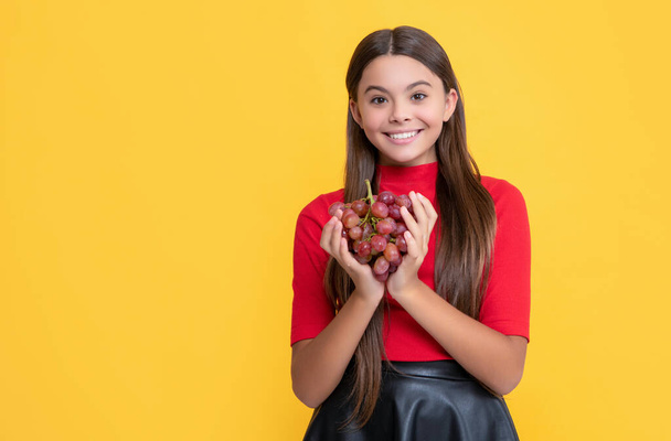 cheerful kid hold bunch of grapes on yellow background. - 写真・画像