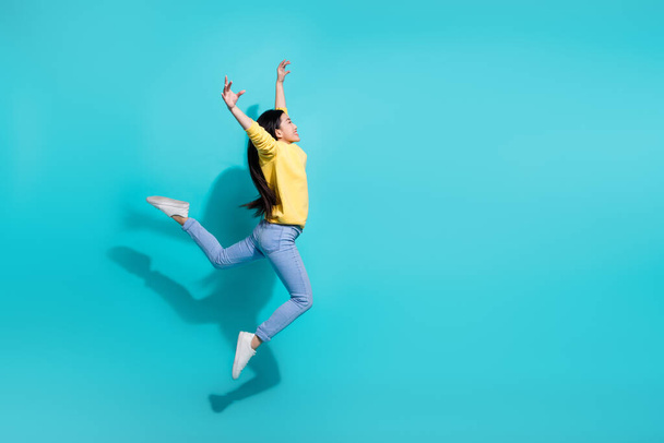 Full length photo of adorable shiny woman wear yellow pullover dancing jumping high empty space isolated teal color background. - Fotoğraf, Görsel