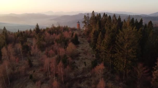 Alba sulla campagna slovacca con vista vicino alla città di Zborov nad Bystrica. Torre in pietra sulla valle di Oravsk magura. Mattina luce morbida arancione. Colpo di droni - Filmati, video
