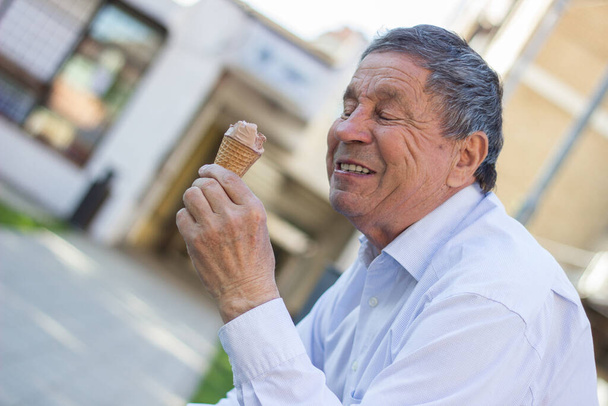 Modern and happy senior Man eating ice cream outdoor on a sunny day - Photo, image