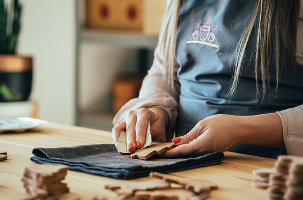 Foto de cerca de las manos de la mujer puliendo con papel de arena Un abeto hecho de arcilla en su estudio - Foto, Imagen