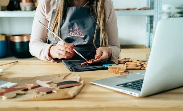 Eine anonyme Geschäftsfrau bemalt einen Stern aus Ton, während sie einen Laptop in ihrem Atelier benutzt - Foto, Bild