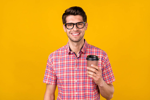 Photo of positive happy young cheerful man wear glasses hold hand coffee cup smile isolated on yellow color background. - Foto, immagini
