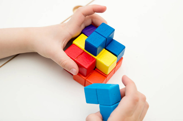 Wooden colorful blocks similar to popular tile-matching puzzle game. Boy matching figures to create new shapes. Montessori type logical game for kids. Brain exercise for preschoolers. - Foto, imagen