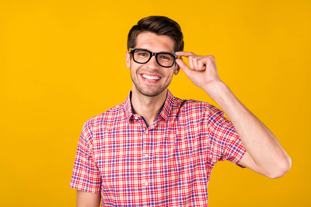 Portrait of attractive cheerful skilled guy geek it specialist wearing touching specs isolated over vibrant yellow color background. - Foto, immagini