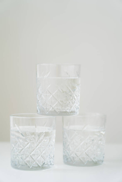 stack of crystal glasses with pure water on white surface isolated on grey - Foto, immagini