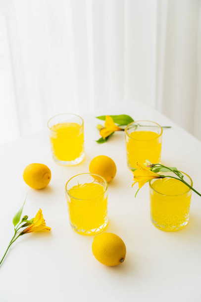 verres à la limonade près de citrons frais et fleurs alstroemeria jaune sur plateau blanc - Photo, image