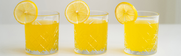 Gläser mit erfrischender Limonade mit saftigen Zitronenscheiben auf weißer Oberfläche isoliert auf grau, Banner - Foto, Bild
