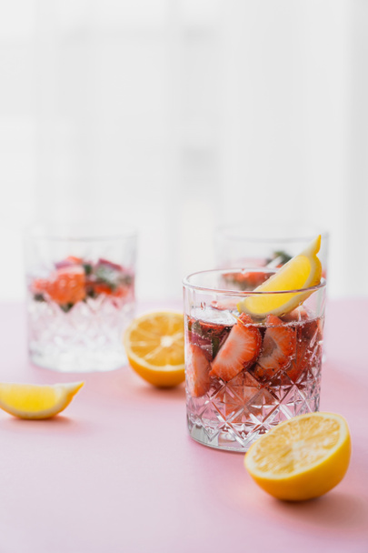 eau tonique avec citron et fraises sur fond flou avec espace de copie blanc - Photo, image
