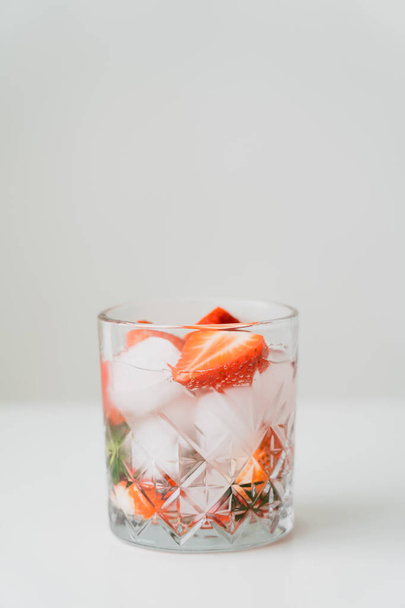 verre à l'eau tonique glacée aux fraises hachées sur surface blanche isolée sur fond gris - Photo, image