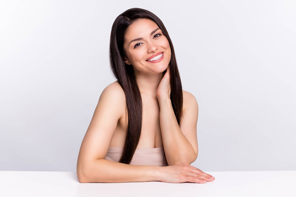 Φωτογραφία πορτρέτο γυναίκα μακριά καστανά μαλλιά χαμογελώντας κάθεται στο τραπέζι απομονωμένο λευκό χρώμα φόντο. - Φωτογραφία, εικόνα
