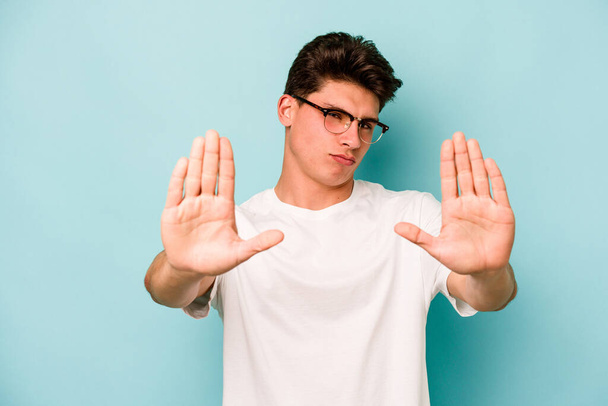 Jonge blanke man geïsoleerd op blauwe achtergrond staan met uitgestrekte hand tonen stopteken, voorkomen dat u. - Foto, afbeelding