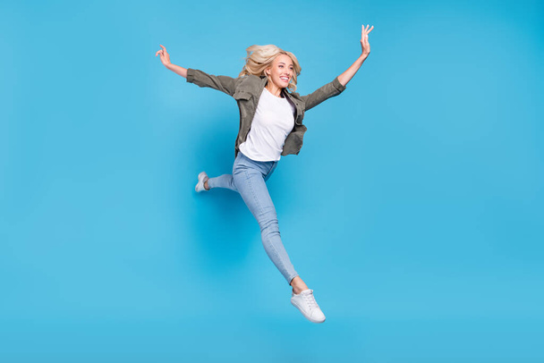 Фотографія повного розміру тіла щаслива жінка стрибає вгору недбало бігаючи ізольований пастельний синій колір фону
. - Фото, зображення
