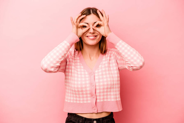Νεαρή καυκάσιος γυναίκα απομονωμένη σε ροζ φόντο ενθουσιασμένος κρατώντας ok χειρονομία στο μάτι. - Φωτογραφία, εικόνα