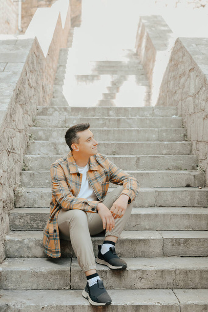 Der Mann sitzt auf der Treppe in der Altstadt. Reise in die alte Burg - Foto, Bild