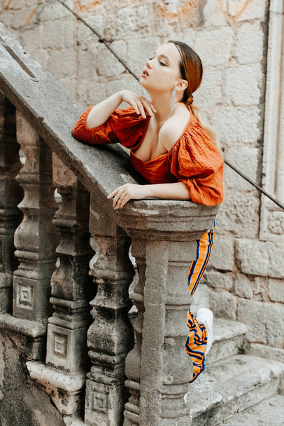 Nádherný portrét krásné ženy ve starém městě na schodech. Dívka s make-upem a účesem, dlouhé stříbrné náušnice - Fotografie, Obrázek