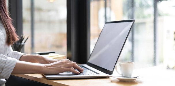 ビジネスマンの女性の手は、空白の白い画面をラップトップにキーボードを入力しています。机の上で働く女性の手のクローズアップ.. - 写真・画像