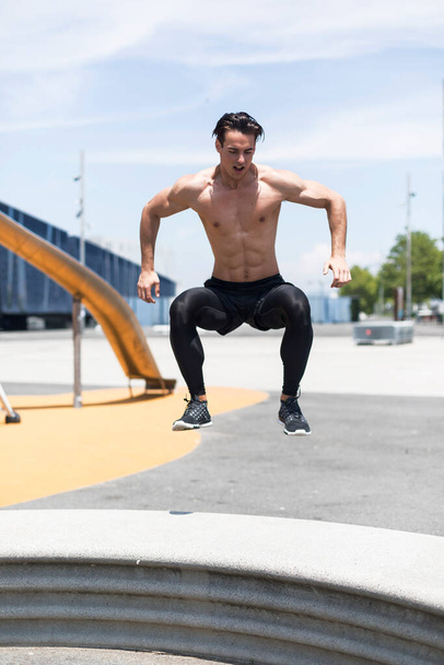 Shirtless athlete working out on cross fit jump box outside on a wall. Muscular man doing box jumps outdoors. - Fotó, kép
