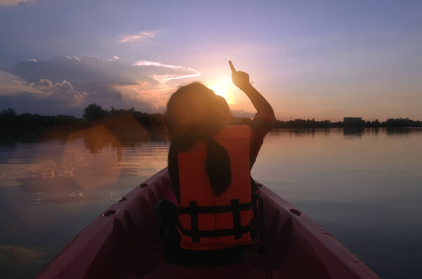 aventura de amor en la naturaleza. niño patio trasero señalando a la salida del sol en kayak barco en el río. - Foto, Imagen