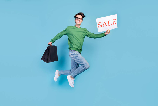 Full length body size photo guy jumping high showing sale carton on shopping isolated pastel blue color background. - Zdjęcie, obraz