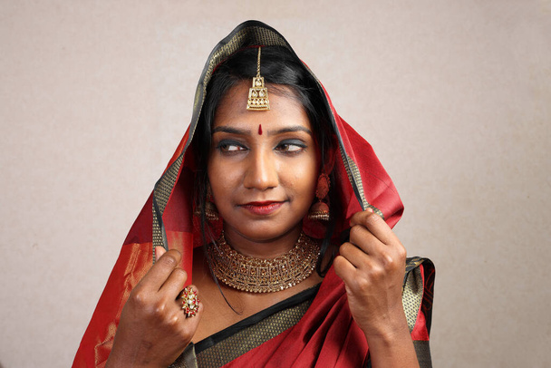 Kırmızı turuncu sari takı takan Hintli kadın. Kolye, jhumka küpe, Maang tikka bel, poz ver. Gülümse.   - Fotoğraf, Görsel