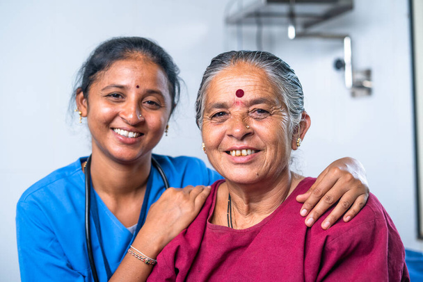 Happy smiling nurse hugging to senior sick women by looking at camera at hospital - concept of bonding, tratment and friendly. - Photo, Image