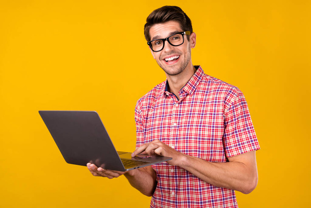 Fénykép a fiatal férfi boldog pozitív mosoly chat típusú projekt e-mail programozó számítógép elszigetelt sárga színű háttér. - Fotó, kép
