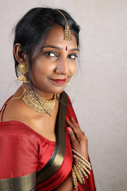 Indiase vrouw dragen rode oranje saree sieraden choker set ketting jhumka oorbel maang tikka taille ketting stand pose look zie glimlach stemming expressie hoofd cover hijab   - Foto, afbeelding