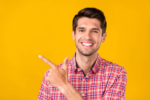 Portrait of attractive cheerful guy demonstrating copy empty space ad advert novelty isolated over bright yellow color background. - Фото, зображення